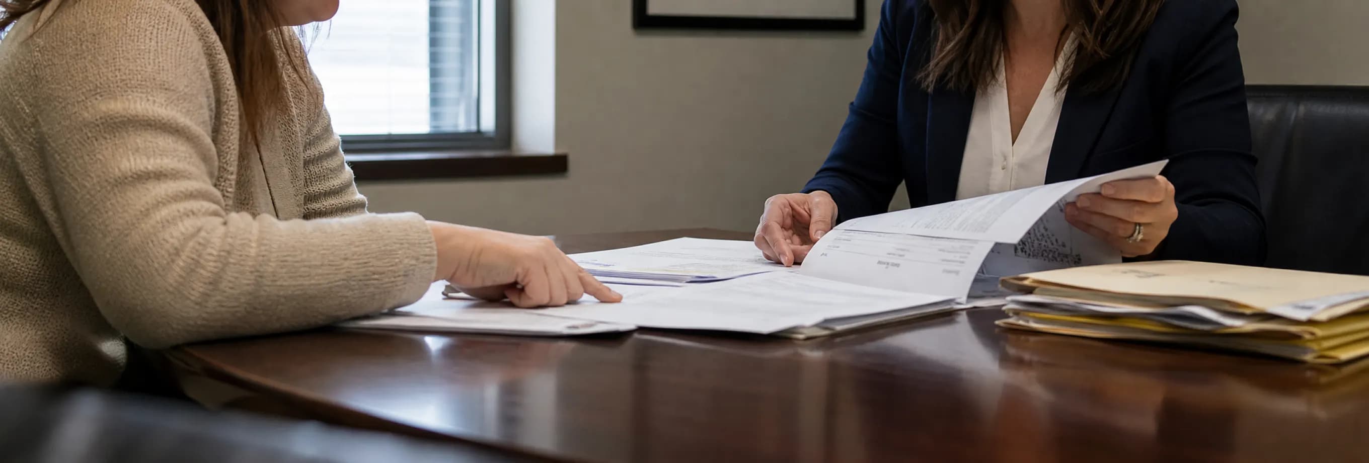 A parent and a family-law attorney reviewing a custody order and hearing minutes at a conference table