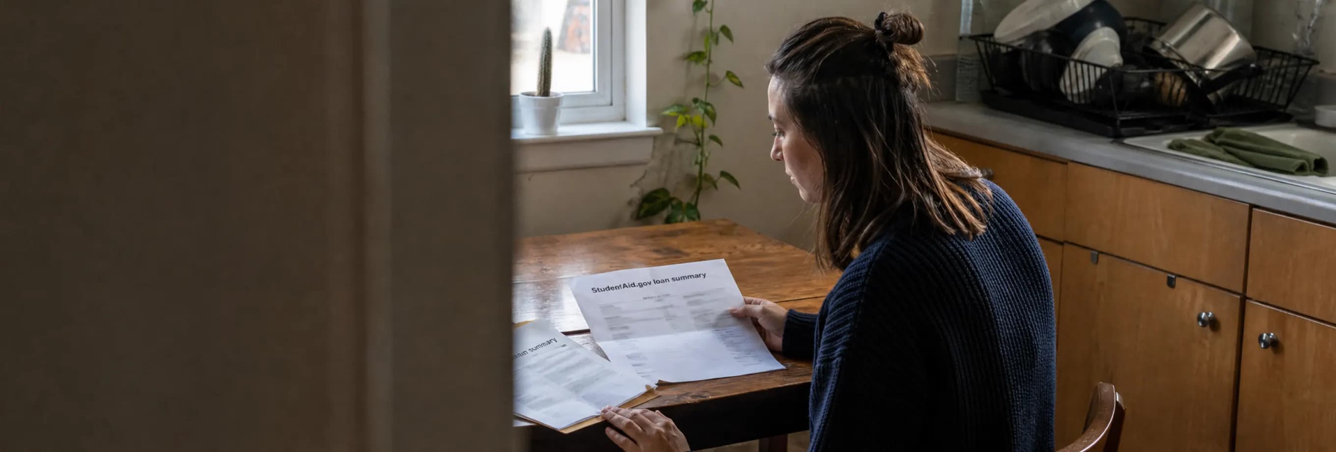 A bankruptcy schedule, a federal loan summary, and a servicer transition notice spread across a kitchen table