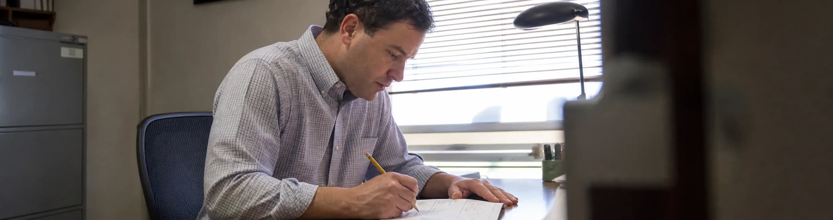 A person writing on a single sheet at a desk in a quiet office